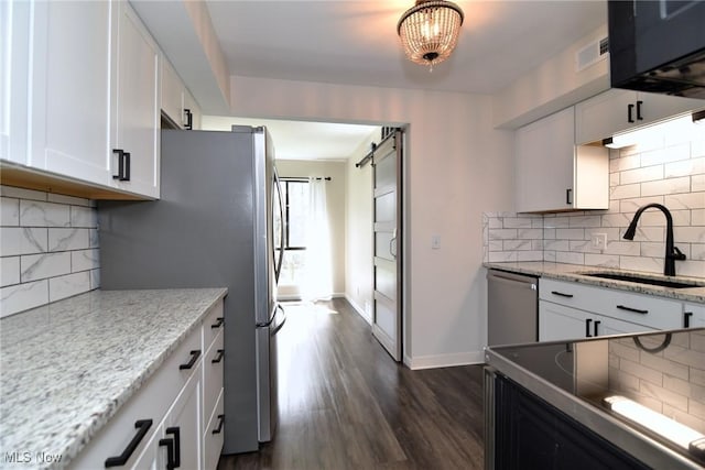 kitchen with decorative backsplash, appliances with stainless steel finishes, a sink, and white cabinetry