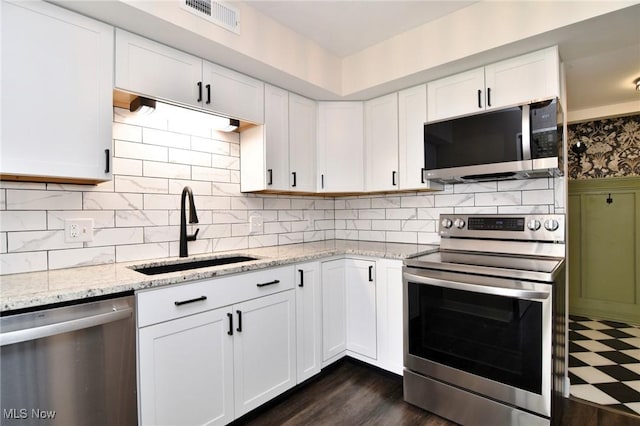 kitchen with a sink, visible vents, white cabinetry, light stone counters, and appliances with stainless steel finishes