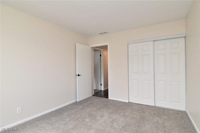 unfurnished bedroom featuring a closet, carpet floors, visible vents, and baseboards