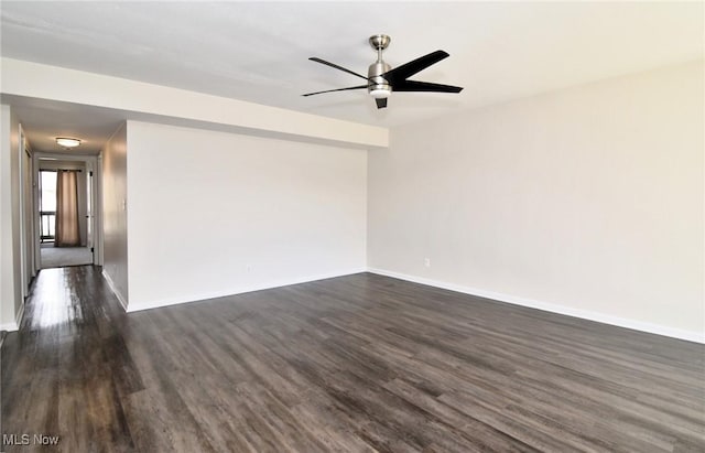 spare room with baseboards, ceiling fan, and dark wood finished floors