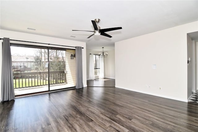 unfurnished living room with ceiling fan with notable chandelier, baseboards, and dark wood-style floors