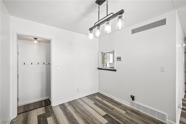 unfurnished dining area featuring dark wood-type flooring, visible vents, baseboards, and a sink