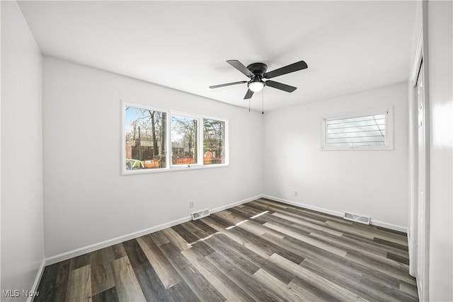 spare room featuring dark wood-type flooring, visible vents, baseboards, and ceiling fan