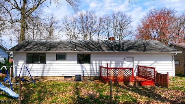 back of property featuring a chimney, a wooden deck, and a playground