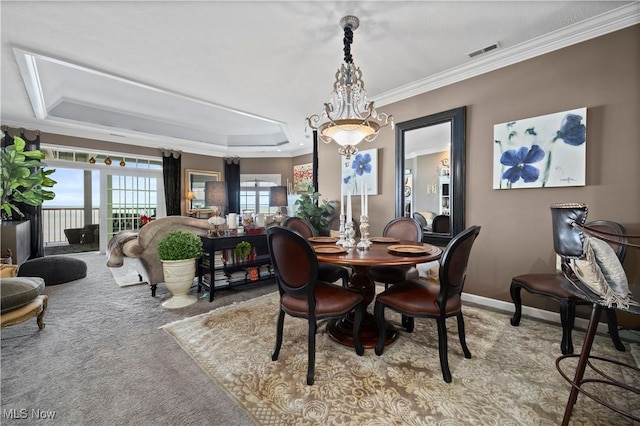 dining room with visible vents, carpet, a chandelier, ornamental molding, and a raised ceiling