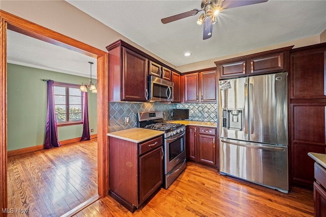 kitchen featuring stainless steel appliances, light wood finished floors, light countertops, a ceiling fan, and tasteful backsplash