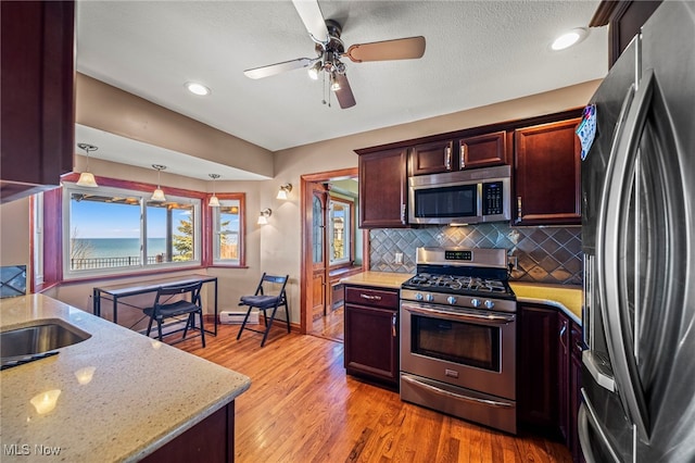 kitchen with stainless steel appliances, baseboards, backsplash, a ceiling fan, and light stone countertops