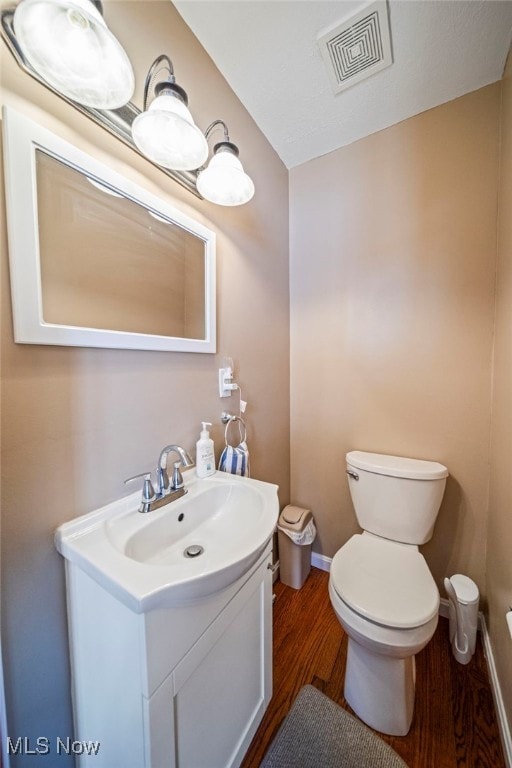 bathroom featuring toilet, wood finished floors, vanity, and baseboards