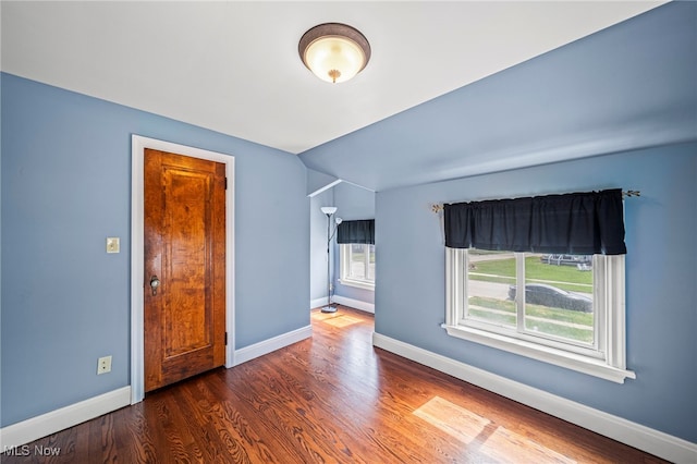 unfurnished room featuring wood finished floors, baseboards, and vaulted ceiling