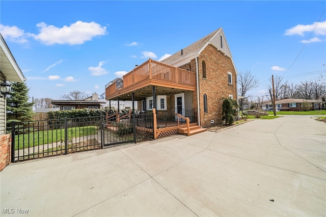 view of home's exterior with brick siding, fence, and a wooden deck