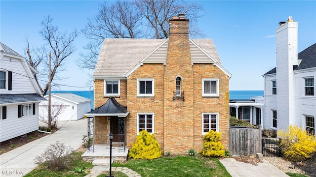 view of front facade featuring brick siding, fence, a chimney, and a garage