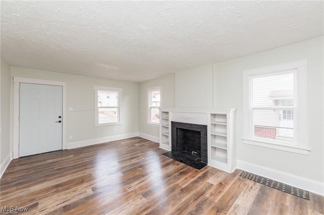 575 Fernwood Dr, Akron, OH 44320 - unfurnished living room with baseboards, wood finished floors, a brick fireplace, and a textured ceiling