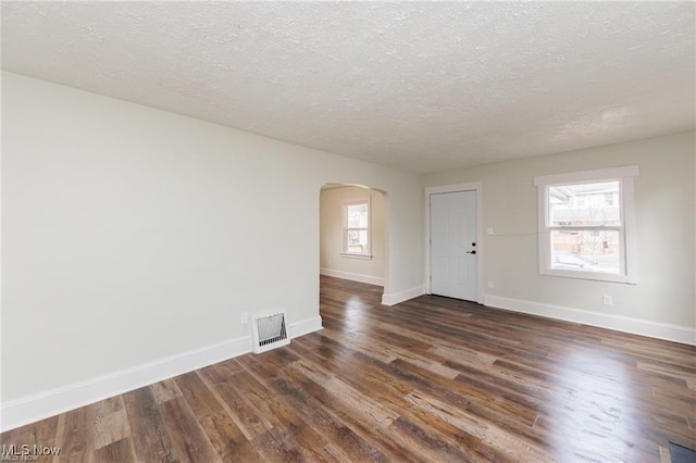 575 Fernwood Dr, Akron, OH 44320 - spare room featuring arched walkways, visible vents, baseboards, and dark wood finished floors