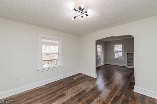 575 Fernwood Dr, Akron, OH 44320 - empty room with arched walkways, baseboards, a textured ceiling, and dark wood finished floors