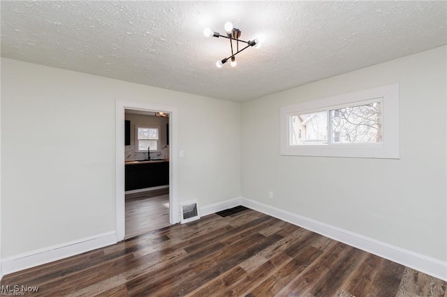 575 Fernwood Dr, Akron, OH 44320 - empty room with dark wood-type flooring, a textured ceiling, visible vents, a sink, and baseboards