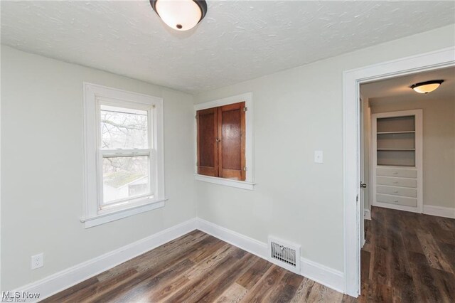 575 Fernwood Dr, Akron, OH 44320 - empty room with dark wood-type flooring, visible vents, and a textured ceiling