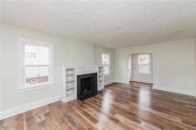 575 Fernwood Dr, Akron, OH 44320 - unfurnished living room with a fireplace with flush hearth, arched walkways, wood finished floors, and baseboards