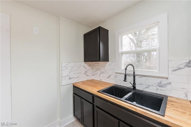 575 Fernwood Dr, Akron, OH 44320 - kitchen with a sink, wooden counters, dark cabinetry, and decorative backsplash