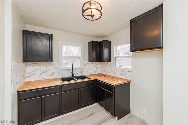 575 Fernwood Dr, Akron, OH 44320 - kitchen featuring a textured ceiling, a sink, backsplash, and wooden counters