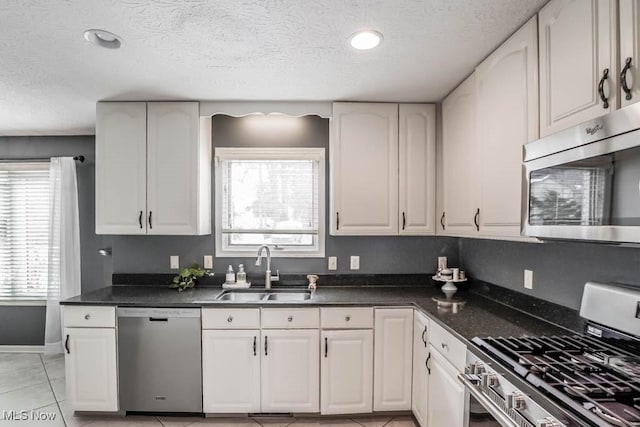 4989 Belden Park Dr NW, North Canton, OH 44720 - kitchen with white cabinets, a sink, dark countertops, a textured ceiling, and stainless steel appliances
