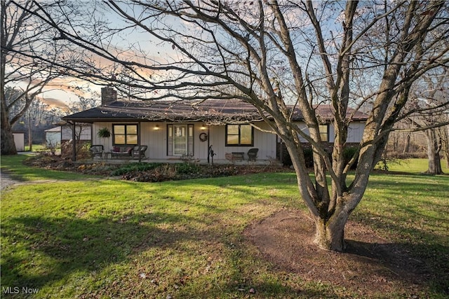 ranch-style house with a porch, a yard, and a chimney