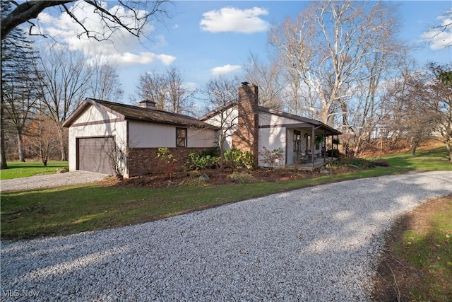 view of side of home featuring a yard, brick siding, driveway, and a chimney