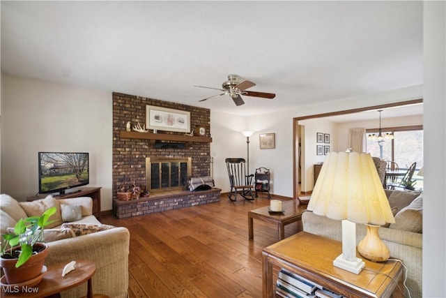 living area featuring ceiling fan with notable chandelier, a fireplace, and wood-type flooring