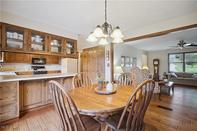 dining area with visible vents, light wood-type flooring, and ceiling fan with notable chandelier