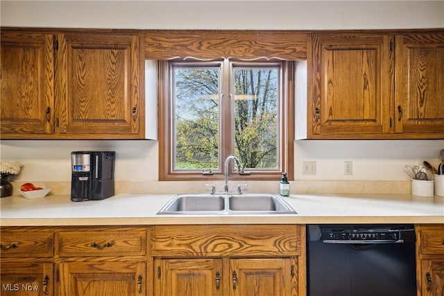 kitchen with light countertops, black dishwasher, a sink, and brown cabinetry