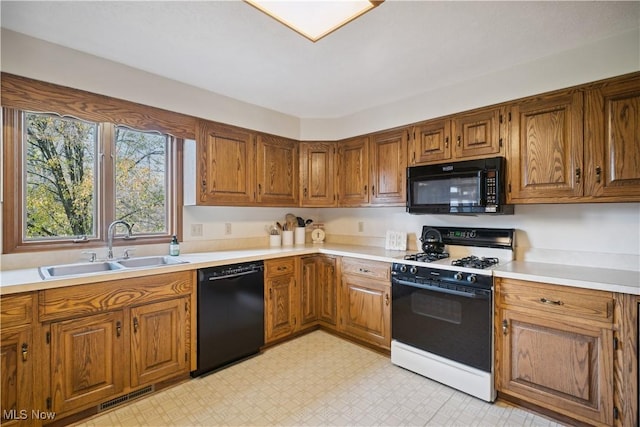 kitchen featuring brown cabinets, visible vents, a sink, and black appliances