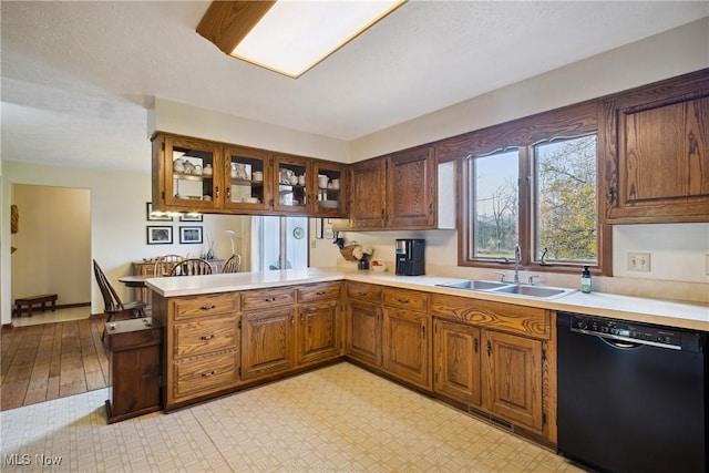 kitchen with visible vents, black dishwasher, a sink, light countertops, and a peninsula