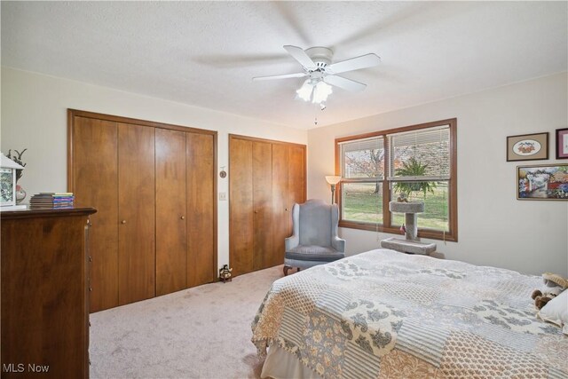carpeted bedroom featuring two closets and a ceiling fan