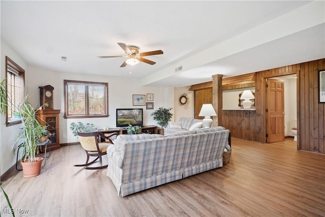 living room featuring visible vents, baseboards, a ceiling fan, wood finished floors, and wood walls