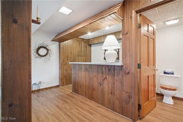 interior space with light wood finished floors, baseboards, and wooden walls