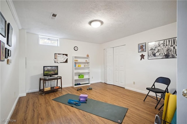 workout room with a textured ceiling, wood finished floors, and baseboards