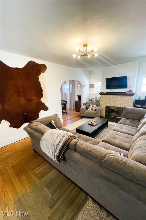 living room with arched walkways, wood finished floors, and a fireplace