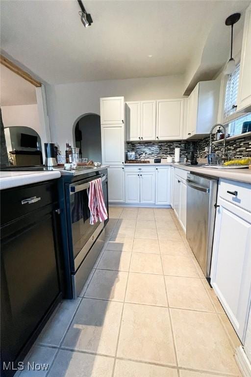 kitchen with a sink, light countertops, white cabinetry, stainless steel appliances, and backsplash
