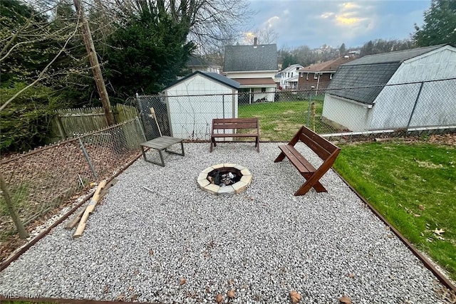 view of yard featuring an outdoor fire pit, an outbuilding, a storage unit, and a fenced backyard