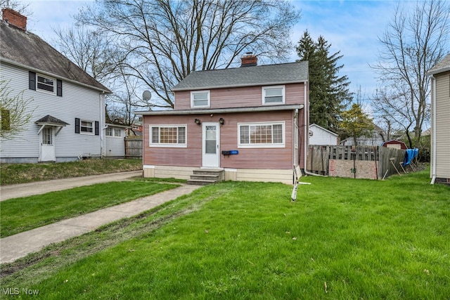 view of front of property with fence, entry steps, a chimney, and a front lawn