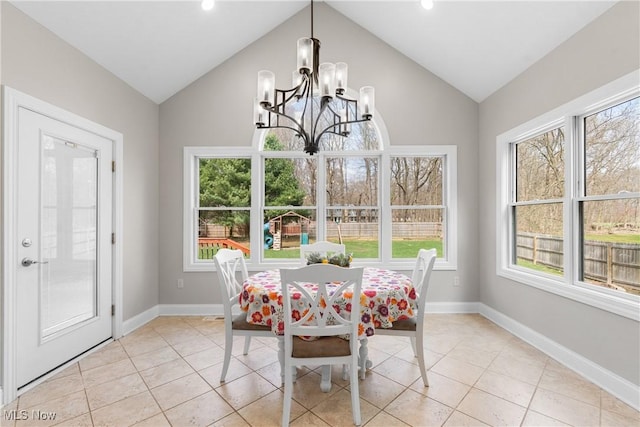 dining area featuring light tile patterned flooring, a notable chandelier, lofted ceiling, and baseboards