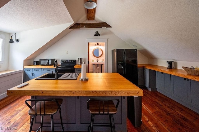 bar with a sink, black appliances, lofted ceiling with beams, and dark wood finished floors