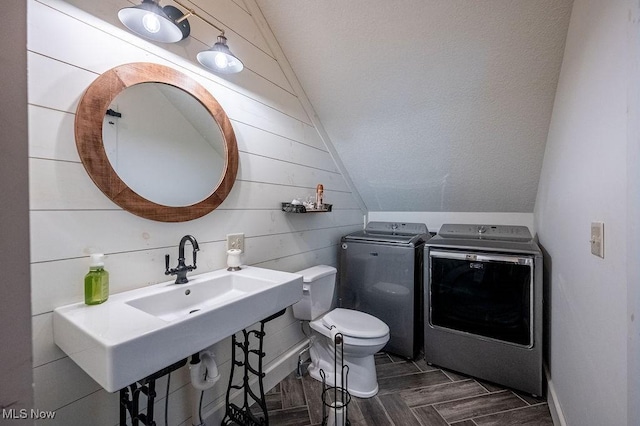 bathroom featuring vaulted ceiling, toilet, wood walls, washer and clothes dryer, and wood finished floors