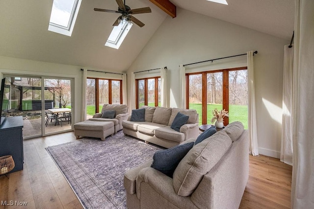 living area featuring light wood-style flooring, beamed ceiling, a skylight, and a ceiling fan