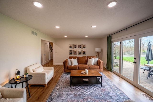 living area featuring a textured ceiling, light wood finished floors, visible vents, and recessed lighting