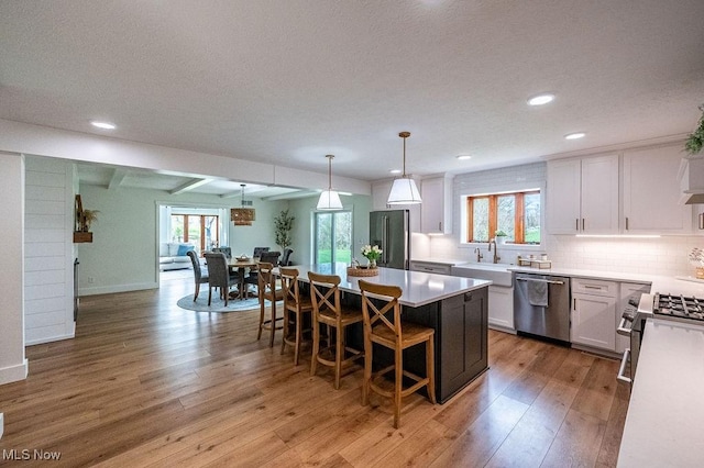 kitchen featuring light wood-style floors, white cabinetry, a breakfast bar, appliances with stainless steel finishes, and open floor plan
