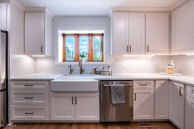kitchen with a sink, light countertops, tasteful backsplash, and dishwasher