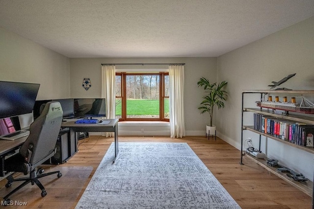 office with a textured ceiling, wood finished floors, and baseboards