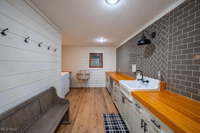 full bathroom featuring a textured ceiling, wood finished floors, vanity, and washer / dryer