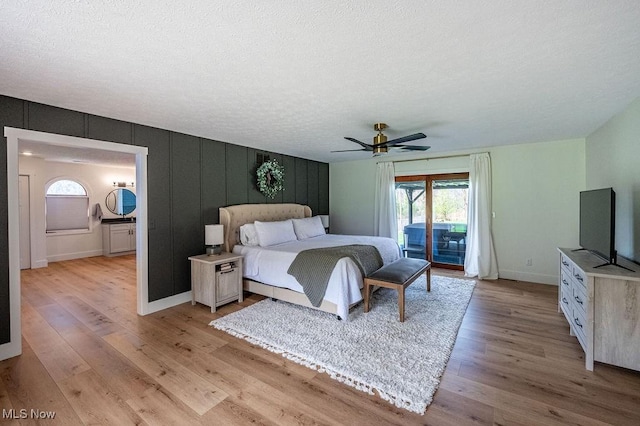 bedroom featuring baseboards, light wood-type flooring, access to exterior, and a textured ceiling