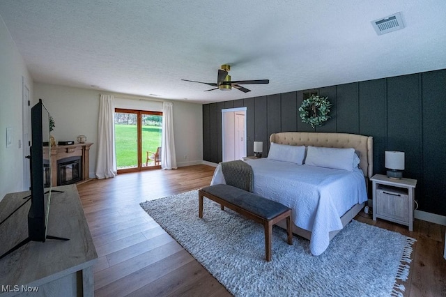 bedroom with visible vents, a ceiling fan, wood finished floors, and a textured ceiling